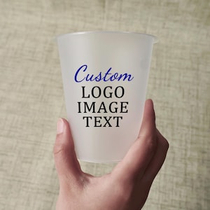May include: A frosted plastic cup held in a hand, with the words "Custom LOGO IMAGE TEXT" printed in blue and black. The cup has a slightly flared rim and a smooth, translucent appearance.