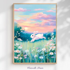 Puede incluir: Una impresión artística enmarcada que representa un conejo blanco saltando por un campo de flores silvestres. El fondo muestra una puesta de sol con nubes rosas y azules. La impresión está etiquetada "Wisterelle Prints" en la parte inferior.