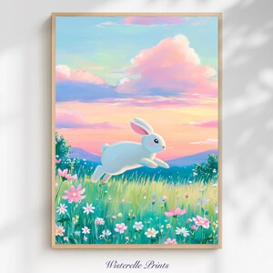 Puede incluir: Una impresión artística enmarcada que muestra un conejo blanco saltando sobre un campo de flores silvestres. El fondo presenta un cielo colorido con tonos rosas y azules. El texto "Wisterelle Prints" está en la parte inferior.