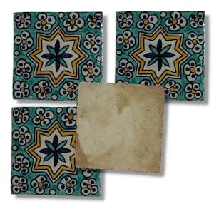 May include: Four square ceramic tiles. Three tiles feature a teal background with a yellow and blue starburst design and white floral accents. One tile is plain with a beige, aged appearance.