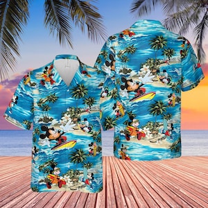 Puede incluir: Una camisa hawaiana azul claro con un estampado de Mickey Mouse surfeando en una playa tropical. La camisa tiene un diseño clásico con botones, cuello en V y mangas cortas. El fondo muestra palmeras, olas y una puesta de sol.