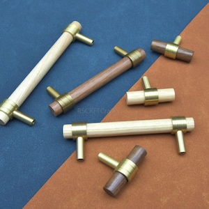 May include: A collection of wooden cabinet pulls with brass accents. Some pulls are light-colored wood, others are dark brown. The brass hardware adds a touch of elegance. The pulls are in various sizes and orientations.