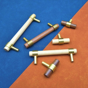 May include: A white ceramic mug with a black handle and the text "But First, Coffee" in a bold, black font. The mug is set against a blurred background, suggesting a cozy setting.