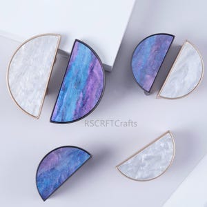 May include: Decorative cabinet pulls in a half-moon shape. The pulls feature a mix of white, blue, and purple marbled designs. Some have gold or black metal frames. The brand name "RSCRFTCrafts" is visible.