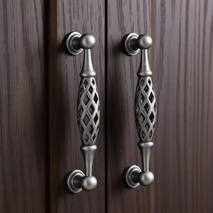 May include: Two antique-style cabinet handles with a silver finish. Each handle has a diamond-patterned center and a curved design. The handles are mounted on a dark brown wooden cabinet door.