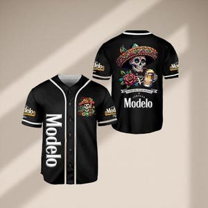 May include: Black baseball jersey with white trim and the word "Modelo" in white down the front. The jersey features a colourful skull design wearing a sombrero and holding a beer, with the Modelo logo.