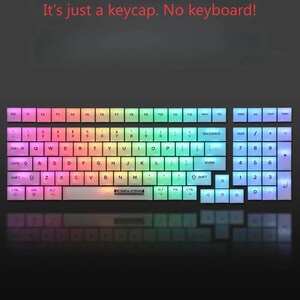 Puede incluir: Un conjunto de teclas de teclado de colores arco&iacute;ris para un teclado mec&aacute;nico. Las teclas est&aacute;n dispuestas para parecerse a un dise&ntilde;o de teclado completo, con letras, n&uacute;meros y teclas de funci&oacute;n. El texto "It's just a keycap. No keyboard!" est&aacute; en la parte superior.