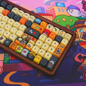 Puede incluir: Un teclado mecánico personalizado con marco de madera y teclas coloridas. Las teclas presentan varios diseños, incluyendo personajes de dibujos animados, alimentos y patrones geométricos. El fondo es una vibrante ilustración de un paisaje urbano.