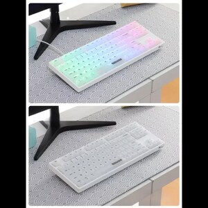 Puede incluir: Un teclado blanco y rectangular con teclas iluminadas. Las teclas est&aacute;n iluminadas con un degradado de arco&iacute;ris en la imagen superior y sin iluminar en la imagen inferior. El teclado est&aacute; sobre un escritorio con una alfombrilla estampada.