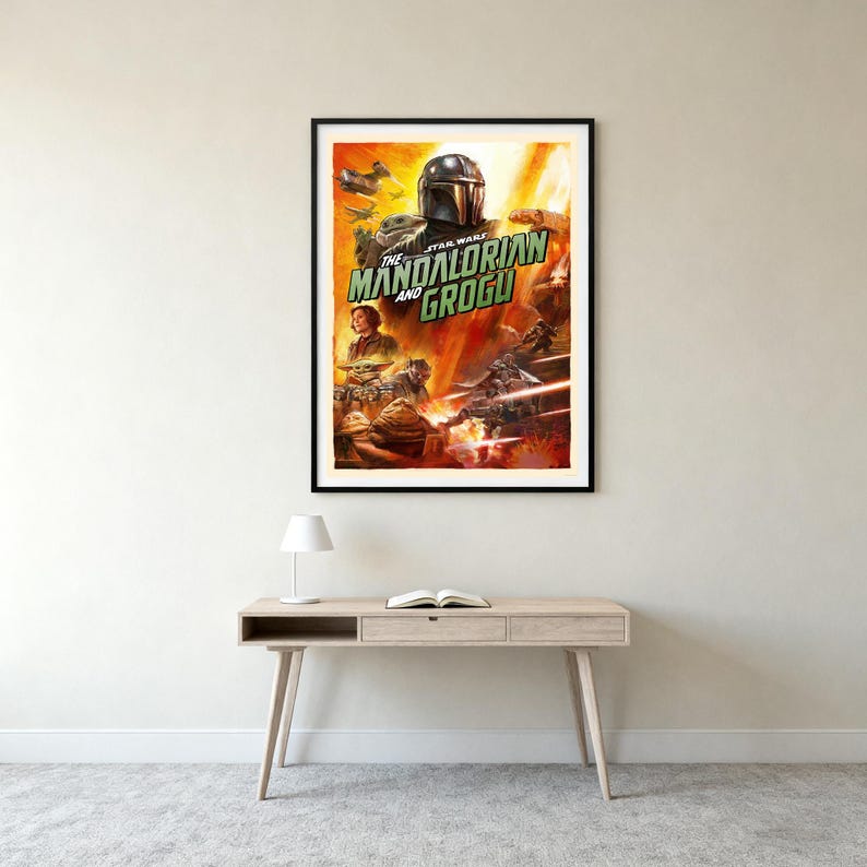 May include: Framed poster for "The Mandalorian and Grogu" from the Star Wars series. The artwork shows the Mandalorian, Grogu, and action scenes against a fiery orange and yellow backdrop. The poster is in a black frame, suitable for a living room.