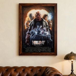 Puede incluir: Póster enmarcado de la película "Hellboy", con los personajes principales en una pose dramática. El póster tiene una combinación de colores oscuros con acentos rojos y azules, y el título se muestra de forma destacada. El marco es marrón oscuro.
