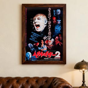 May include: Framed movie poster for Hellraiser 2, featuring Pinhead with pins in his head. The poster has Japanese text and various horror imagery. It is presented in a dark brown wooden frame.