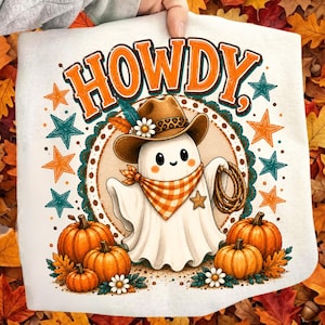 Puede incluir: Una camiseta blanca con el gráfico de un fantasma que lleva un sombrero de vaquero marrón con banda de leopardo y un pañuelo a cuadros naranja. El fantasma sostiene un lazo. El texto HOWDY aparece arriba, rodeado de estrellas naranjas y azul verdoso.