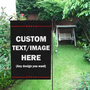 May include: A black garden flag with the text "CUSTOM TEXT/IMAGE HERE" in white. The flag has red star accents and the text "(Any design you want)". The flag is displayed in a garden setting with green grass and trees.