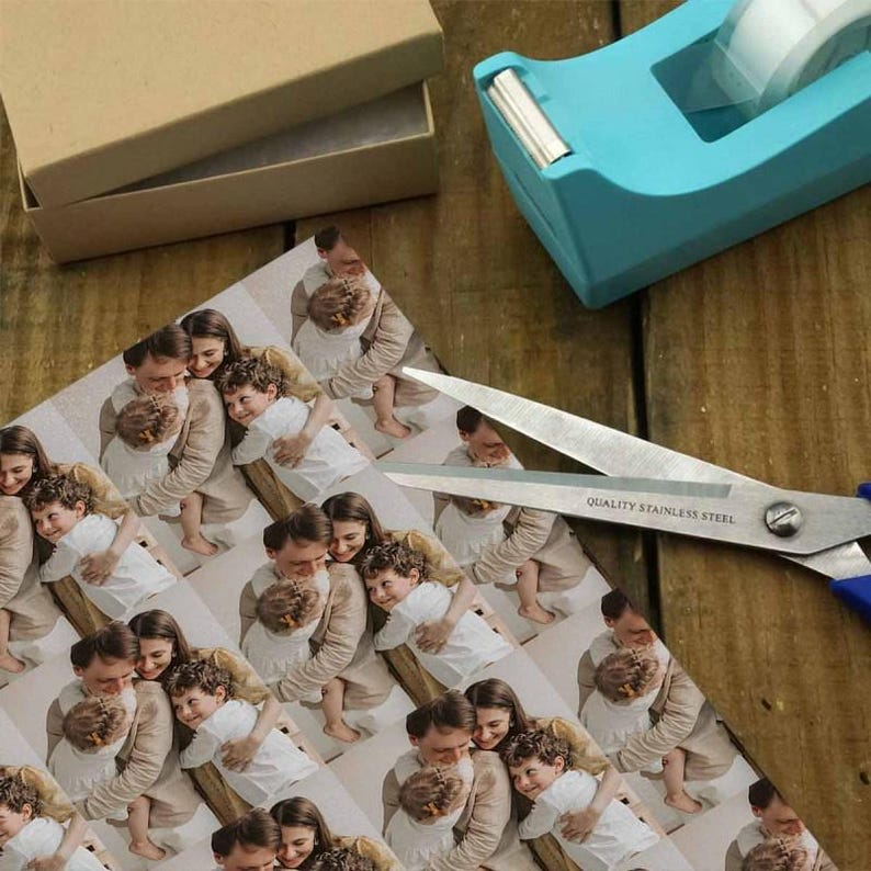 May include: A sheet of patterned paper featuring a repeating image of a family hugging, with scissors, a tape dispenser, and a cardboard box. The scissors are stainless steel with blue handles. The tape dispenser is turquoise.