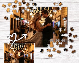 May include: A custom photo puzzle featuring a romantic image of a couple embracing, with a smaller image of the same photo. The puzzle pieces are scattered around the image, with a heart-shaped graphic. The puzzle is on a white wooden surface.