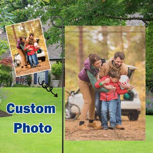 May include: A garden flag featuring a family portrait. The image shows a family of three, with a child holding a ball. The flag has the words "Custom Photo" in blue and white.