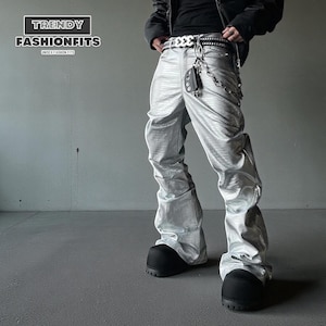 Puede incluir: Pantalones plateados metálicos con acabado texturizado. Los pantalones tienen un diseño de pierna ancha y se combinan con botas negras. Se ve un cinturón blanco con cadena plateada y un accesorio negro. El texto "TRENDY FASHIONFITS" es visible.