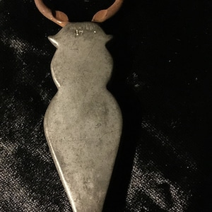 May include: A silver bottle opener with a copper handle. The opener is shaped like a person and has the word "PEWTER" and the number "17" engraved on it.