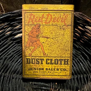 May include: A vintage rectangular tin with a yellow background and the words "Red Devil" in red script. The tin features an illustration of a devil and the words "Dust Cloth". The text "Junior Sales Co. Los Angeles, Calif. Made in U.S.A." is also visible.