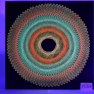 Op de afbeelding: Een cirkelvormig draadkunstwerk met concentrische ringen in teal, oranje en goud tegen een zwarte achtergrond. Het kunstwerk heeft een centraal gat en een geweven uiterlijk. De tekst "25/01" staat rechtsonder.