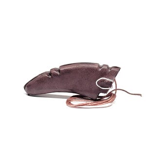 Könnte beinhalten: Ein dunkelburgunderfarbener Leder-Fingertab, entworfen für das Bogenschießen. Der Tab hat eine einzigartige Form mit strukturierter Oberfläche und einer Metallschlaufe zur Befestigung einer Schnur. Eine braune Schnur ist befestigt.