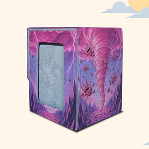May include: A rectangular deck box featuring a vibrant purple and pink illustration of a swirling tornado lifting small, horned, pink creatures into a stormy sky. The box has a textured surface, stitched edges, and a grey rectangular front panel.