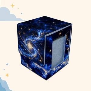 May include: A square deck box for trading cards featuring a deep blue space theme with a bright central star, swirling nebulae, and golden orbital rings. The exterior has a smooth finish with a flap closure and a grey interior lining.