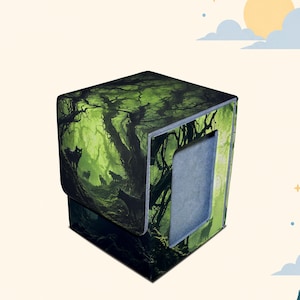Può includere: Un contenitore quadrato per mazzi di carte con una scena di foresta scura e sagome di lupi su uno sfondo verde vibrante. La scatola presenta un coperchio pieghevole e un'apertura rettangolare sul pannello frontale che rivela una superficie interna grigia.