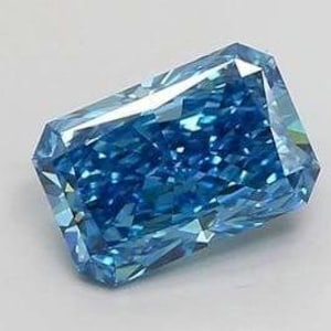 Op de afbeelding: Een radiant-geslepen, fancy vivid blauwe diamant. De edelsteen heeft een rechthoekige vorm met meerdere facetten, die licht reflecteren. De kleur van de diamant is een diep, verzadigd blauw, tegen een witte achtergrond.