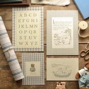 May include: A collection of children's stationery and decor items, including alphabet cards, illustrated storybook pages, and a teddy bear card. The items feature a blue and white gingham and striped pattern, with a vintage aesthetic.