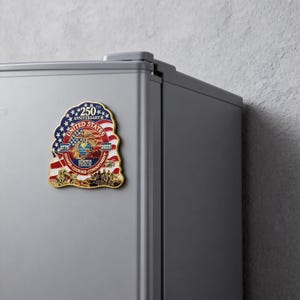 K&ouml;nnte beinhalten: Ein Gedenkmagnet zum 250. Jahrestag der Vereinigten Staaten. Der Magnet zeigt die US-Flagge, einen Adler und die Worte "Ehre, Mut, Engagement" und "Semper Fidelis". Der Magnet ist an einem grauen K&uuml;hlschrank befestigt.