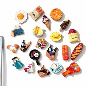 Puede incluir: Un conjunto de imanes de nevera con temática de comida. Los imanes representan alimentos como un huevo frito, helado, pan y una taza de café. Los imanes están hechos de resina y están diseñados para parecer alimentos en miniatura.