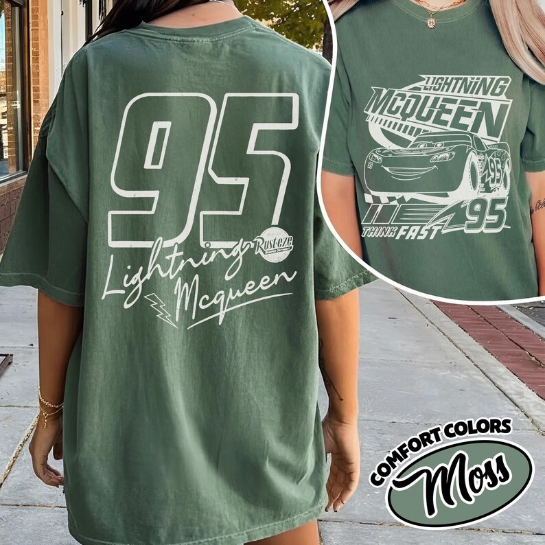 May include: Green t-shirt with the number 95 and the words "Lightning McQueen" in white. The shirt also features a graphic of Lightning McQueen on the front. The shirt is a Comfort Colors Moss colour.