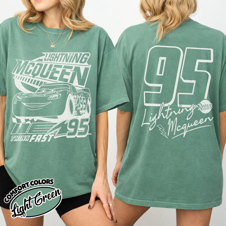 May include: Light green t-shirt with Lightning McQueen design. The front features the character and text, the back has a large "95" and "Lightning McQueen" text. The shirt is a Comfort Colors brand.