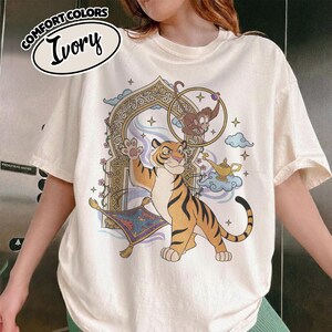 May include: A white ceramic mug with a black handle and the text "But First, Coffee" in a black, handwritten-style font. The mug is on a white surface.