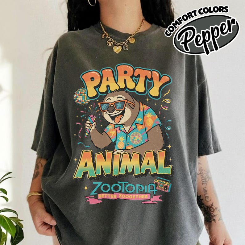 May include: Dark gray t-shirt with a colorful graphic featuring a sloth wearing sunglasses and a Hawaiian shirt, holding a microphone. The text reads "PARTY ANIMAL ZOOTOPIA BETTER ZOOGETHER". The shirt has the words "COMFORT COLORS Pepper" in a circle.