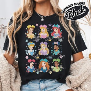 May include: Black t-shirt featuring illustrations of Disney princesses, including Belle, Aurora, and Ariel, with their names in cursive script. The shirt has the words "Comfort Colors" and "Black" in a circular design.