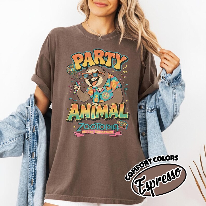 May include: Brown t-shirt with a graphic of a sloth wearing sunglasses and a Hawaiian shirt, holding a microphone. The text reads "PARTY ANIMAL ZOOTOPIA BETTER ZOOOGETHER". The shirt is labeled "Comfort Colors Espresso".