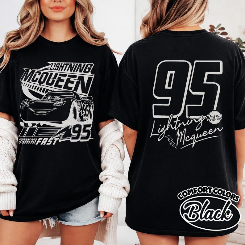 May include: Black t-shirt with Lightning McQueen design. The front shows the character, number 95, and "Lightning McQueen". The back has a large "95" and the character's name. The shirt is labelled "Comfort Colors Black". A classic tee for fans of the Cars movie.