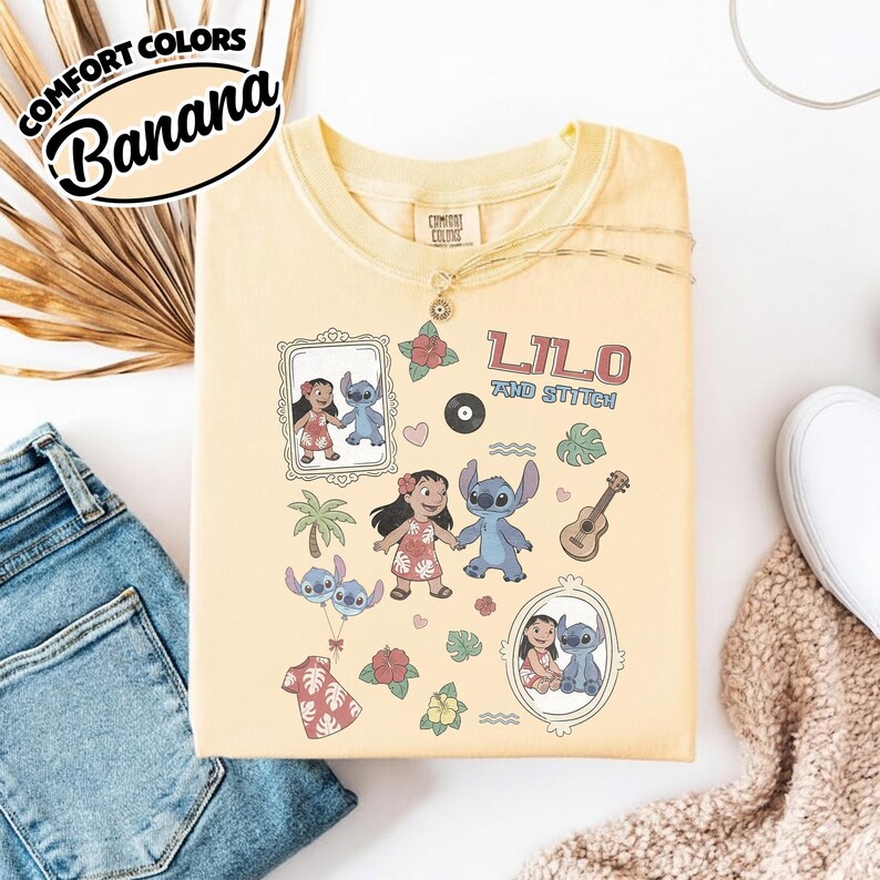 Puede incluir: Una camiseta amarilla Comfort Colors con un dise&ntilde;o con las palabras "Lilo and Stitch" e ilustraciones de los personajes. La camiseta tiene cuello redondo y mangas cortas. La camiseta est&aacute; tendida sobre una superficie blanca.