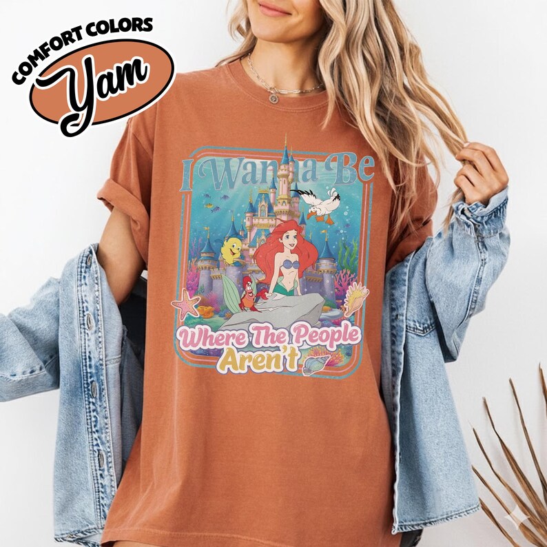 Puede incluir: Camiseta de color &oacute;xido con un gr&aacute;fico colorido de Ariel de La Sirenita, con el texto "I Wanna Be Where The People Aren't". La camiseta tiene un dise&ntilde;o vintage y desgastado. Las palabras "Comfort Colors" y "Yam" est&aacute;n impresas arriba a la izquierda.