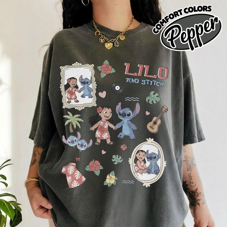 Puede incluir: Camiseta gris oscuro con el texto "Lilo and Stitch" e ilustraciones de dibujos animados de Lilo y Stitch. La camiseta incluye im&aacute;genes de una palmera, flores, una guitarra y un disco. Las palabras "Comfort Colors" y "Pepper" tambi&eacute;n est&aacute;n impresas en la camiseta.