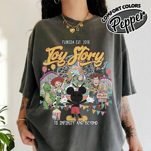 May include: A white ceramic mug with a black handle and the text "But First, Coffee" in a bold, black font. The mug is set against a blurred background, suggesting a cosy setting.