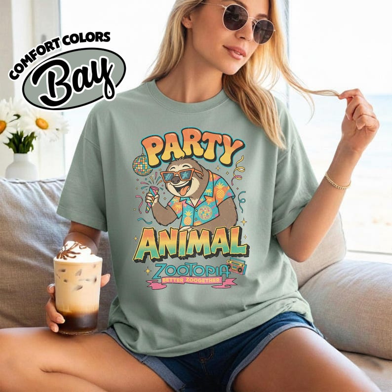 May include: A light green t-shirt with the text "PARTY ANIMAL" and a cartoon sloth wearing sunglasses and a Hawaiian shirt. The shirt also has the text "ZOOTOPIA" and "BETTER ZOOGETHER".