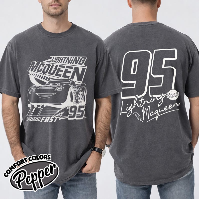 May include: Dark grey t-shirt with a white Lightning McQueen graphic and the number 95. The front displays "Lightning McQueen" and "Think Fast". The back features the number 95 and "Lightning McQueen" in script. The shirt is a comfort colors style.
