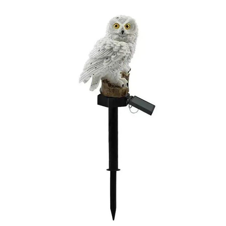 May include: A white owl garden stake with yellow eyes and a black stake. The owl is perched on a brown tree stump. A small solar panel is attached to the stake. The garden stake is designed for outdoor use.