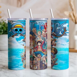 May include: Three stainless steel tumblers with white straws. Each tumbler features a different design from the anime series One Piece. The designs include the series logo, characters, and nautical elements, all set against a blue ocean and sky background.