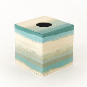 Peut inclure: Un couvre-boîte à mouchoirs carré avec un motif peint de rayures horizontales dans des tons de bleu, vert et blanc.