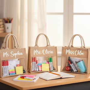 May include: Three tan burlap tote bags with clear plastic windows, each featuring white script text reading Ms. Sophia, Mrs. Olivia, and Miss Chloe. The bags contain various office supplies including markers, sticky notes, and a small blue cup.